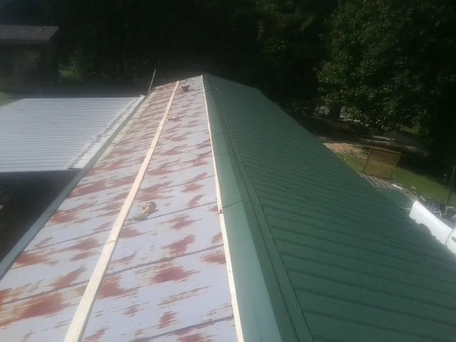 Old rusted panels beside newly installed green metal roofing — Wind Damage Roof Repair by Roofing Brothers in Saint Louis