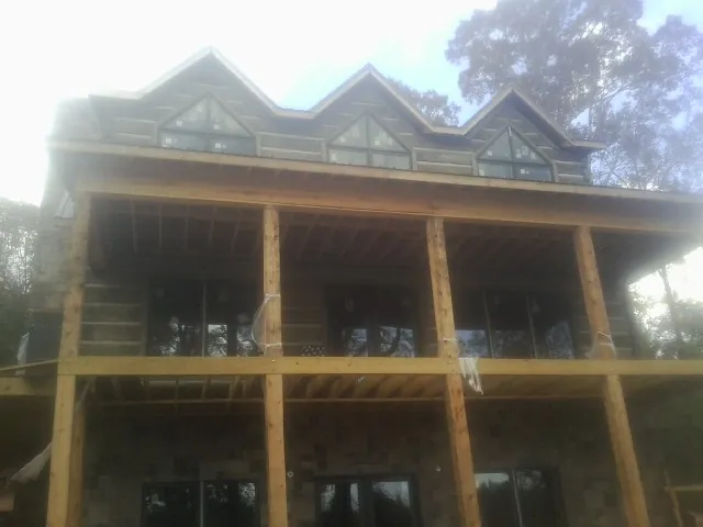 Dormers and porch framing on a large log home under construction — Roof Coating work by our crew in Saint Louis